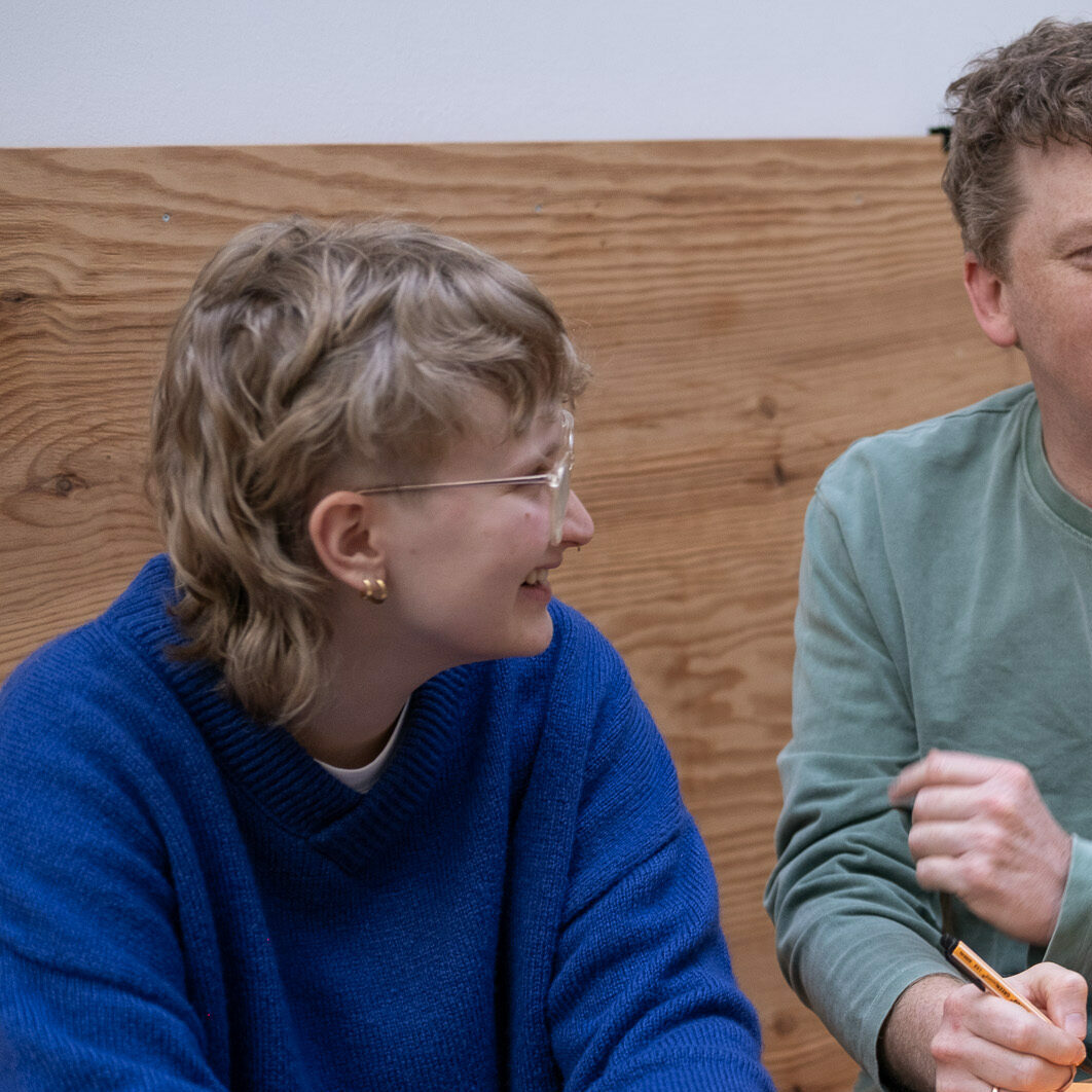 Drei Personen unterhalten sich an einem Tisch in einem Team Workshop in Stuttgart