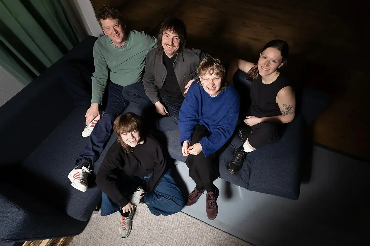 Das Traffo-Team, Coaching und Unternehmensberatung in Stuttgart, sitzt lachend auf dem Sofa.